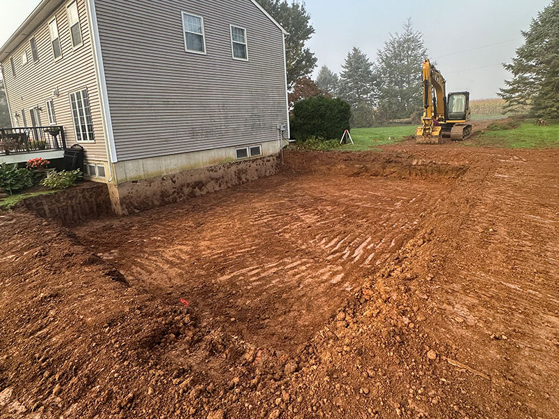 Excavator backfilling a yard next to a house