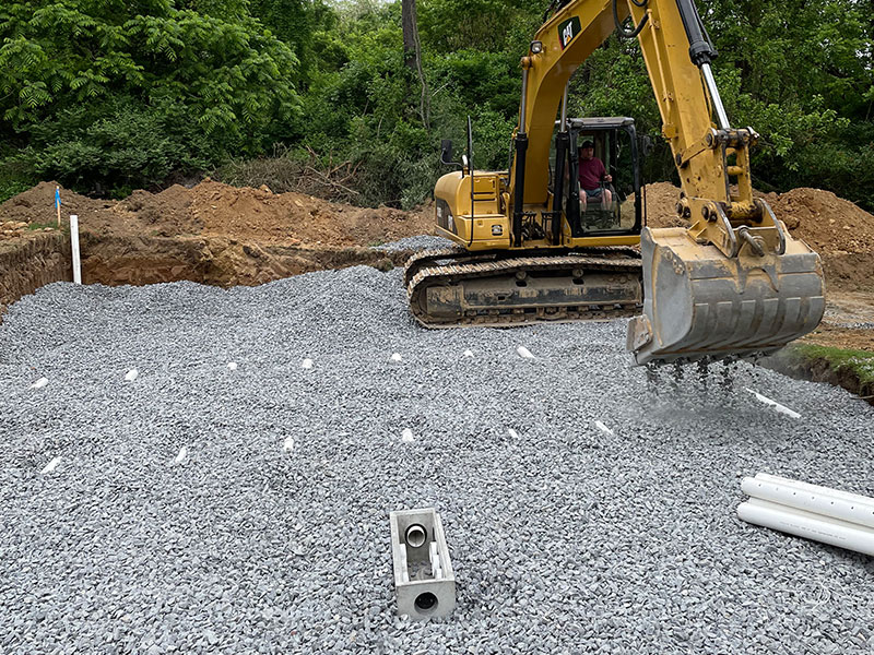 excavator covering septic system with gravel